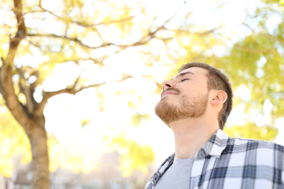 Relaxed man is breathing fresh air outdoors